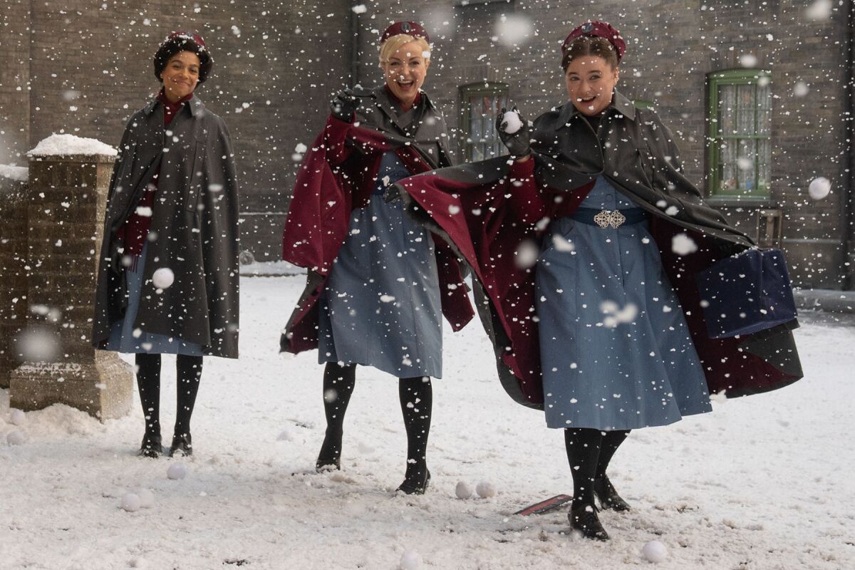 Lina Hargreaes, left, Helen George and Leonie Elliott wearing nurses uniforms in a snowy scene. 