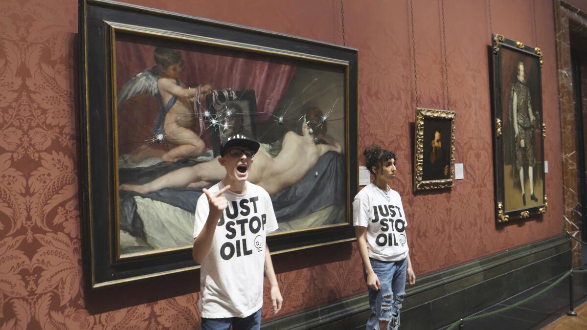 Two people stand by a painting wearing "Just Stop Oil" T-shirts.
