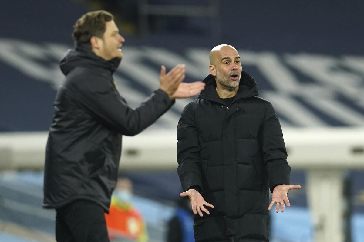 Manchester City's head coach Pep Guardiola, right, gestures during the Champions League, first leg, quarterfinal soccer match between Manchester City and Borussia Dortmund at the Etihad stadium in Manchester, Tuesday, April 6, 2021. (AP Photo/Dave Thompson)