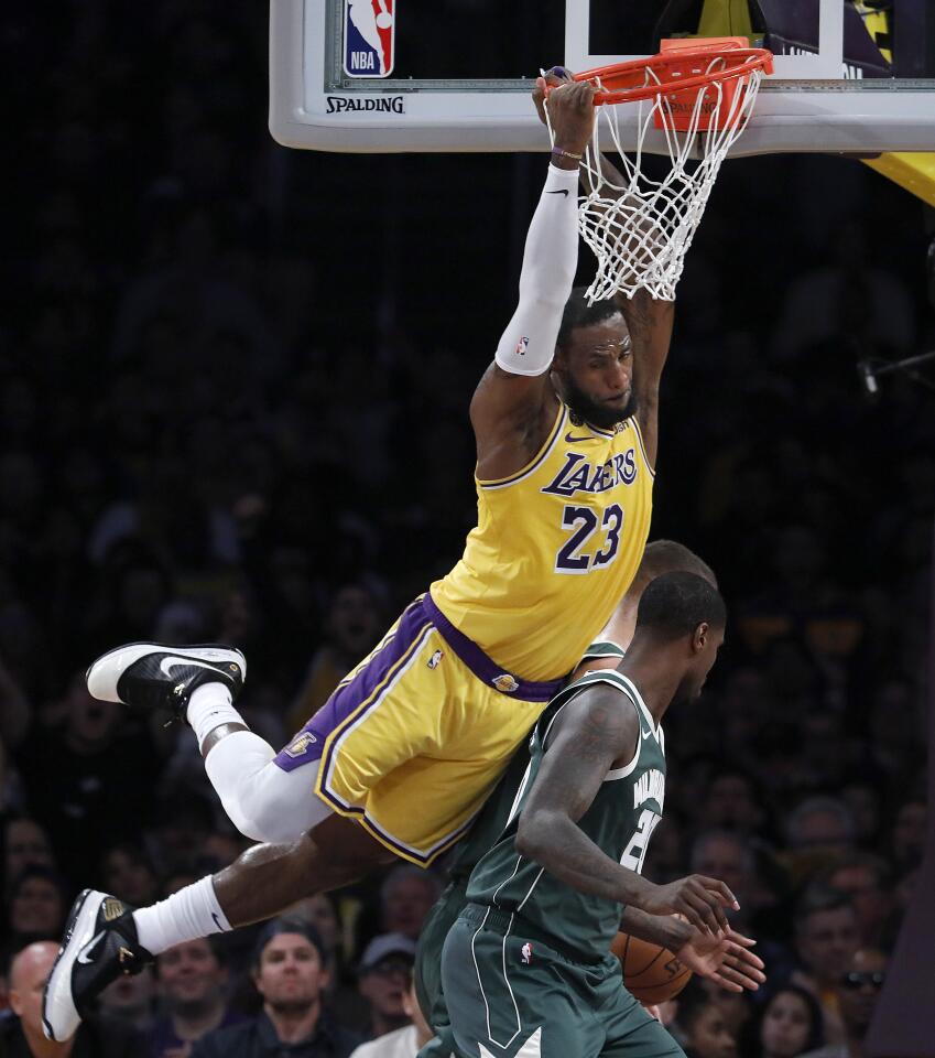 LeBron James swings from the rim after dunking during the first half of a game March 6 against the Bucks at Staples Center.