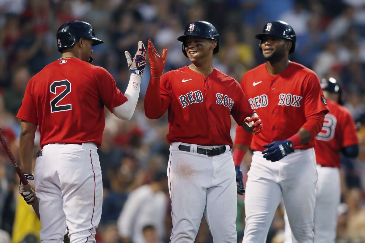 Boston Red Sox's Rafael Devers, center, celebrates with Xander Bogaerts (2) after hitting a three-run home run that also drove in Franchy Cordero, right, during the fourth inning of a baseball game against the Oakland Athletics, Tuesday, June 14, 2022, in Boston. (AP Photo/Michael Dwyer)