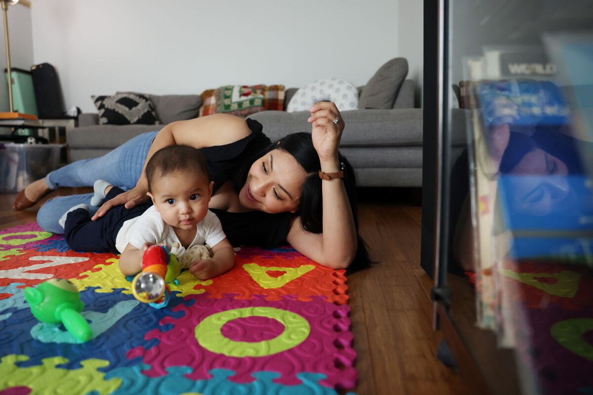 A mother plays on the floor with her 6-month-old son.