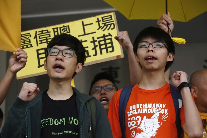 Student leaders Joshua Wong, right, and Nathan Law shout slogans outside a court in Hong Kong on July 17. The activists and two other defendants appeared in court after being charged with obstructing police officers as they took part in an anti-China protest in June 2014.