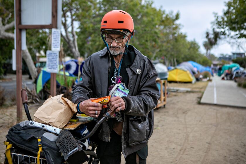 VENICE, CA - MAY 23: Curtis E. stands with his bike on the edge of the homeless encampment outside Abbot Kinney Memorial Branch Library on Monday, May 23, 2022 in Venice, CA. Curtis says he was one of the first people to start living in the encampment. (Jason Armond / Los Angeles Times)