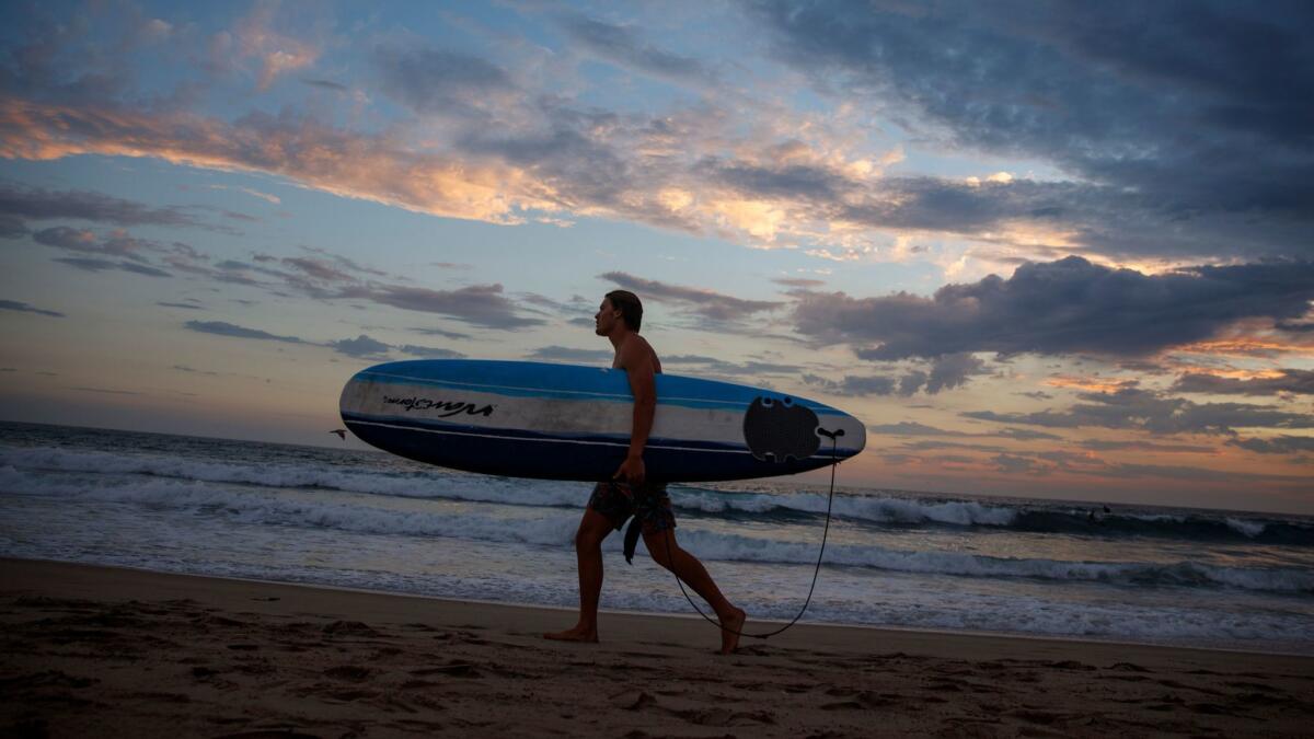 Ryder Mora exits the water after surfing in Manhattan Beach.