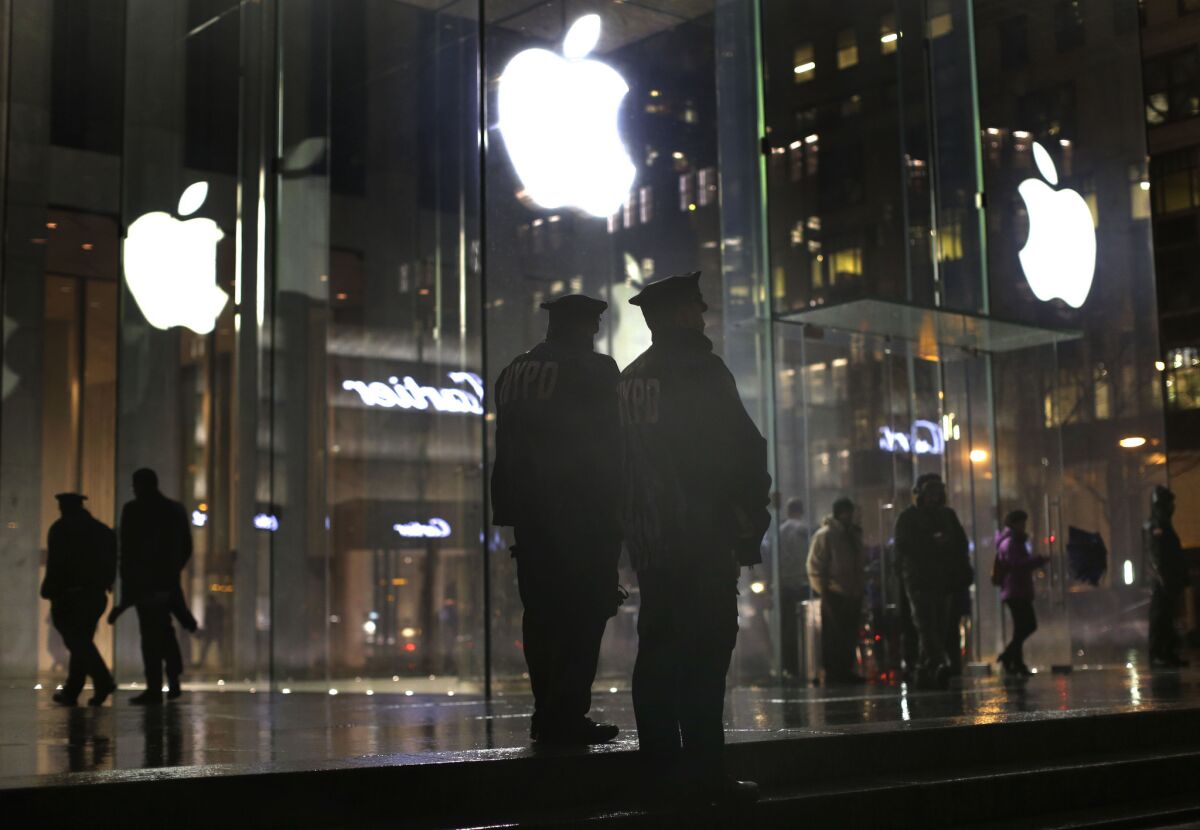 Police officers stand outside an Apple Store on Fifth Avenue in New York while monitoring a rally by supporters of Apple's stance against the FBI on Tuesday.