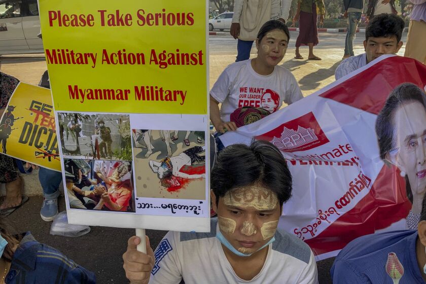 An anti-coup protester holds a placard requesting military action against Myanmar military in Yangon, Myanmar Thursday, Feb. 25, 2021. Protesters against the military's seizure of power in Myanmar were back on the streets of cities and towns on Thursday as regional diplomatic efforts to resolve Myanmar's political crisis intensified Wednesday. (AP Photo)