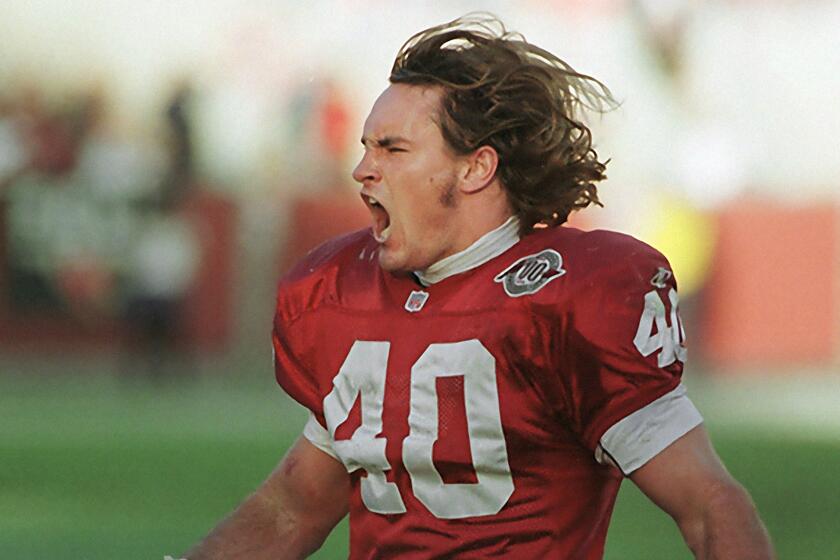 ADVANCE FOR WEEKEND EDITIONS APRIL 30-MAY 1 - FILE - In this Dec. 20, 1998, file photo, Arizona Cardinals safety Pat Tillman celebrates after tackling New Orleans Saints running back Lamar Smith for a loss in the third quarter of an NFL football game in Tempe, Ariz. Pat Tillman became an inspiration when he walked away from a lucrative NFL career to fight for his country after the Sept. 11 terrorist attacks, a decision that ultimately cost the football star turned soldier his life. Now Tillman’s legacy lives on through the parents who have named their children after him. (AP Photo/Roy Dabner, File)