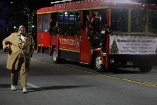 Huntington Park, CA - December 09: Council Member Juan Munoz-Guevara walks alongside a trolly of Southeast City Elected Officials during the Huntington Park Christmas Parade on Saturday, Dec. 9, 2023 in Huntington Park, CA. (Michael Blackshire / Los Angeles Times)