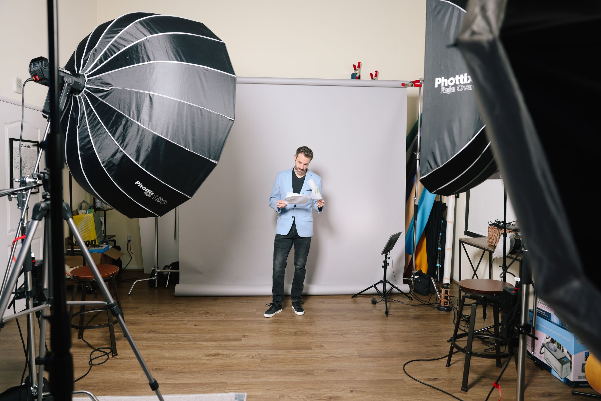 एक आदमी फोटो स्टूडियो में एक स्क्रिप्ट लिए खड़ा है।