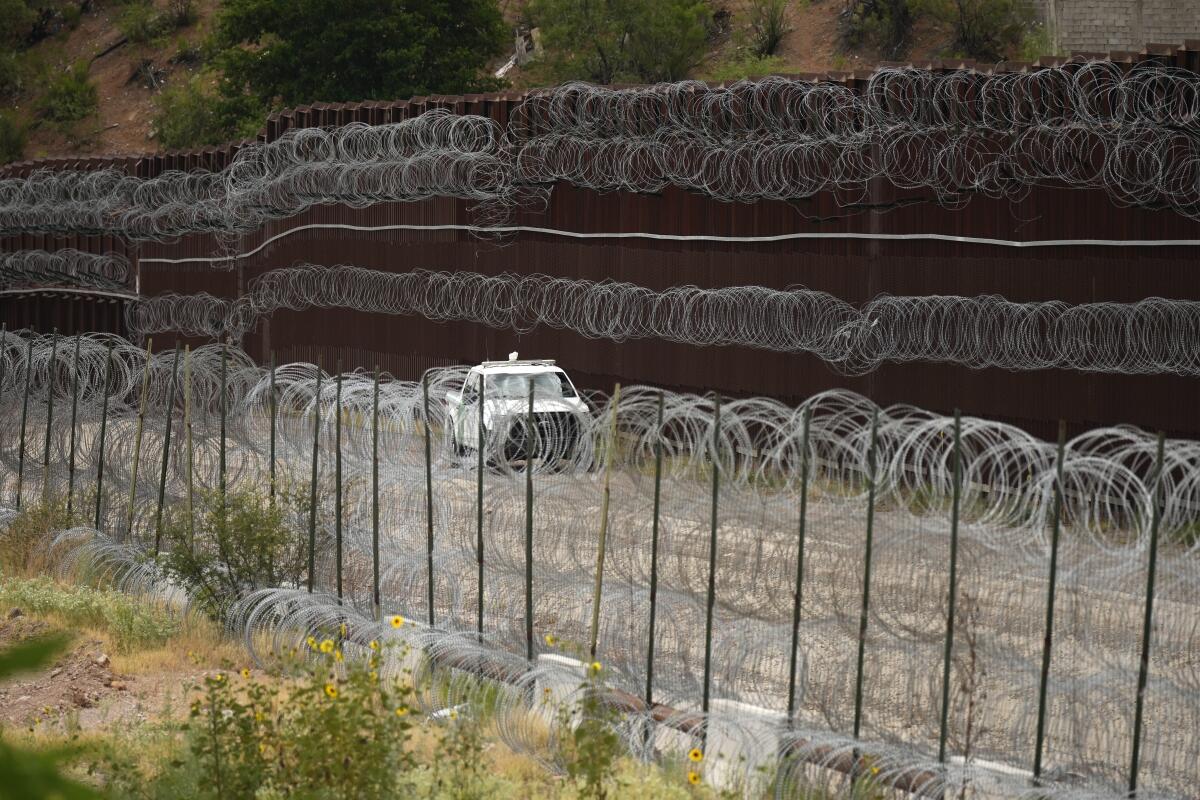 ARCHIVO - Un vehículo pasa junto al muro fronterizo de Estados Unidos en Nogales, 