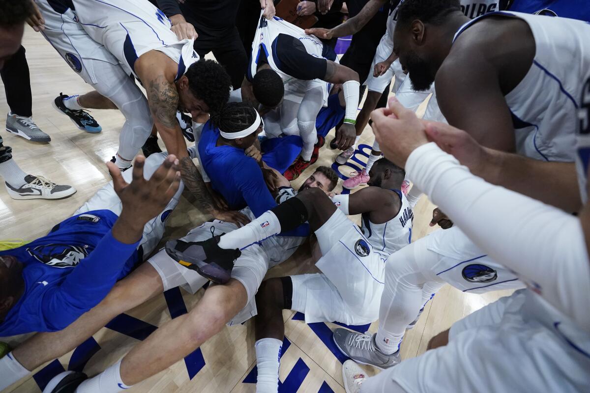 Dallas Mavericks players mob Maxi Kleber, center, after his three-pointer.