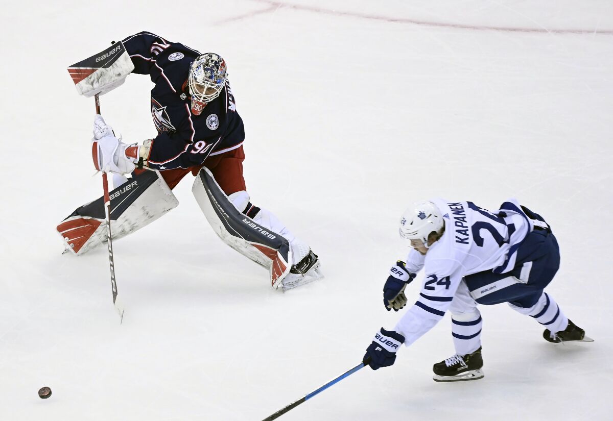 Columbus Blue Jackets goaltender Elvis Merzlikins (90) comes far out of his net to play the puck as Toronto Maple Leafs right wing Kasperi Kapanen (24) chases during the second period of an NHL hockey playoff game Thursday, Aug. 6, 2020, in Toronto. (Nathan Denette/The Canadian Press via AP)