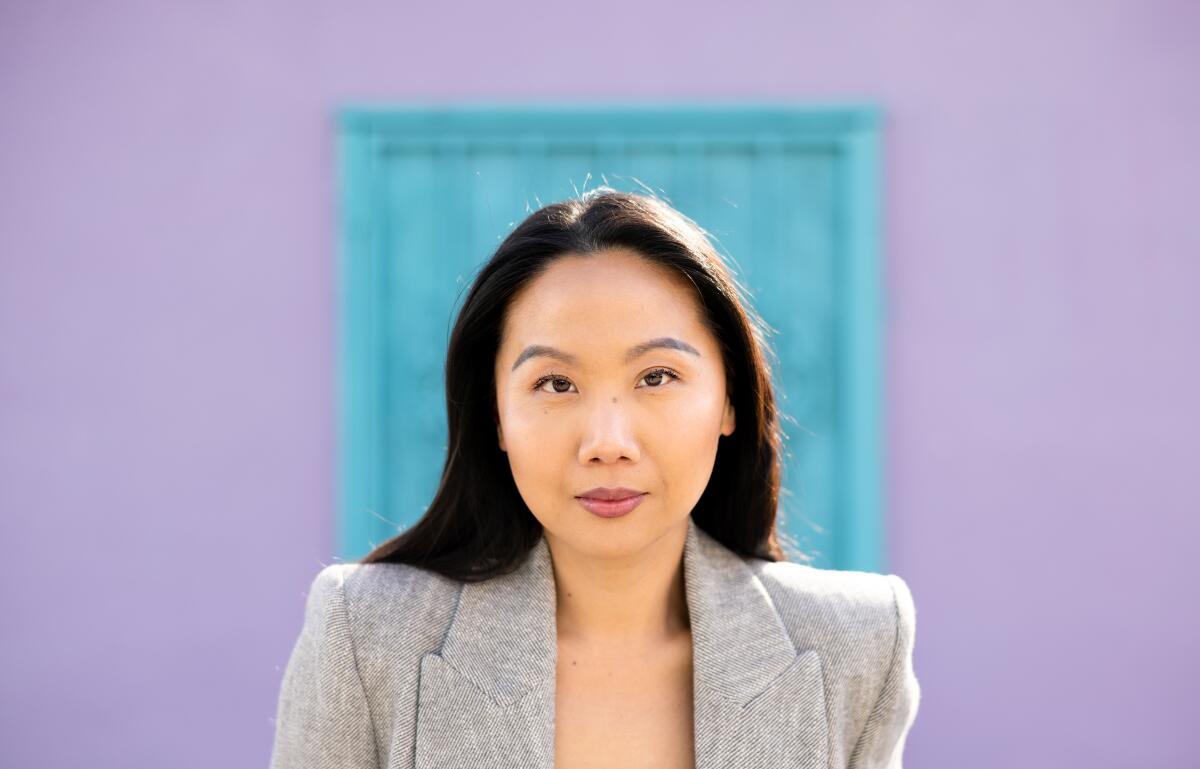 Woman in gray business suit in front of a purple and blue wall
