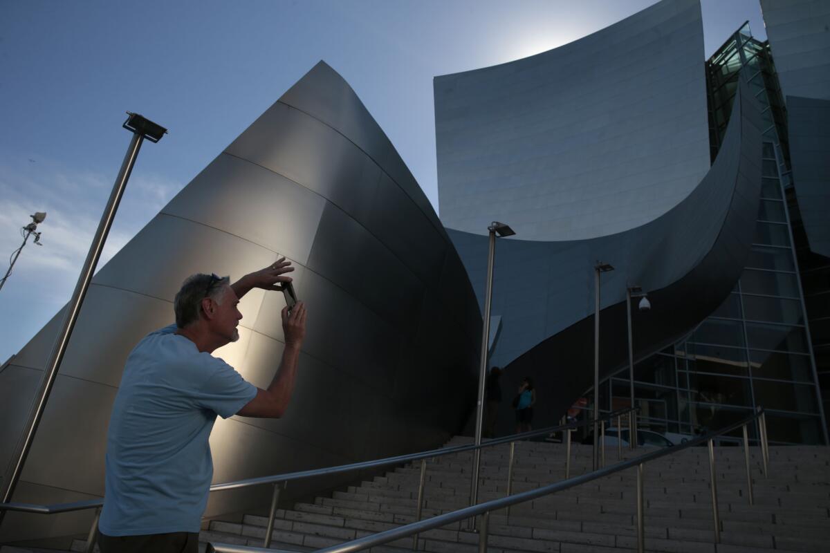 Bill Miers of Bellingham, Wash., snaps a photo outside Walt Disney Concert Hall in downtown Los Angeles on Friday. High-temperature records fell across Southern California on Friday and the region could see more record highs over the weekend.