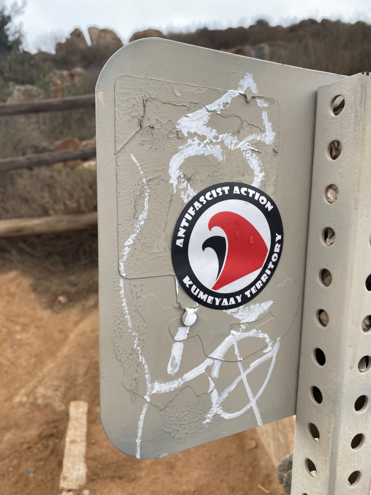 A sticker with a typical "Antifa" logo — except with waves replacing the black and red flags — on Cowles Mountain.