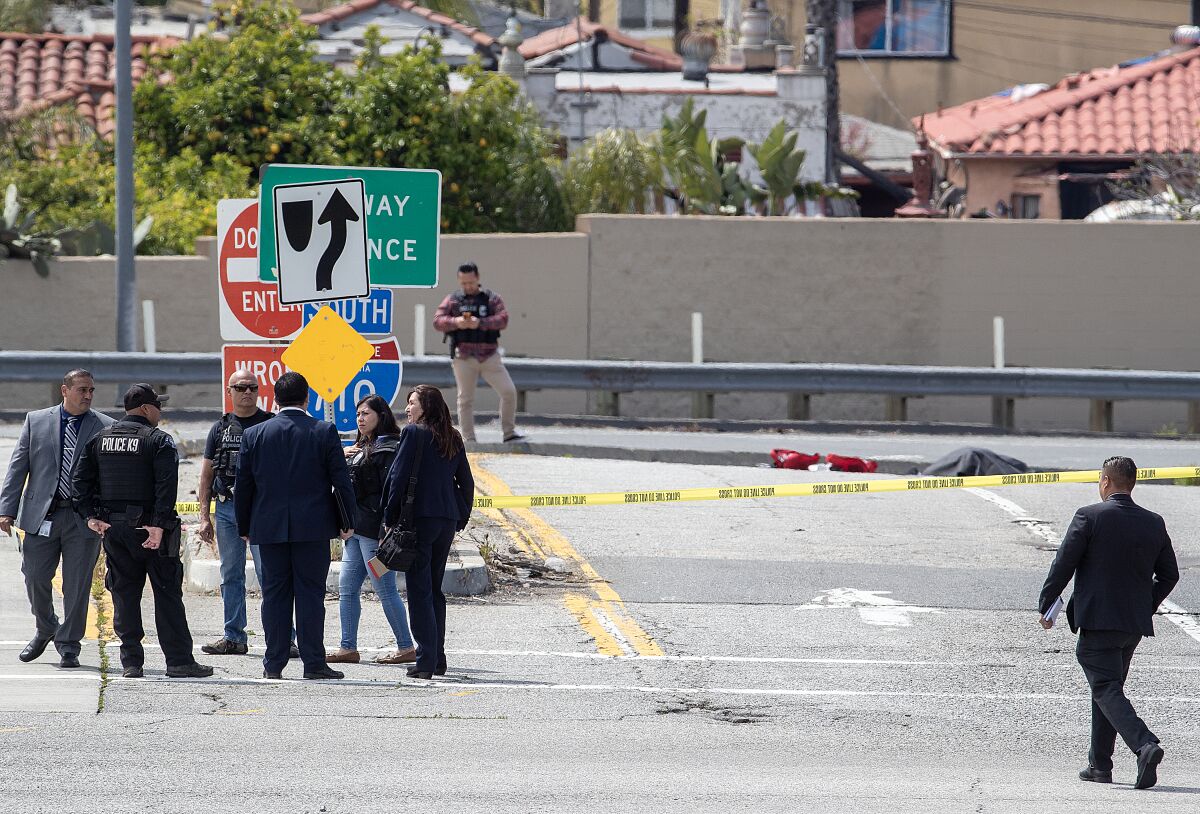 Police work near the scene where a body lies under a tarp on the 710 Freeway southbound onramp.