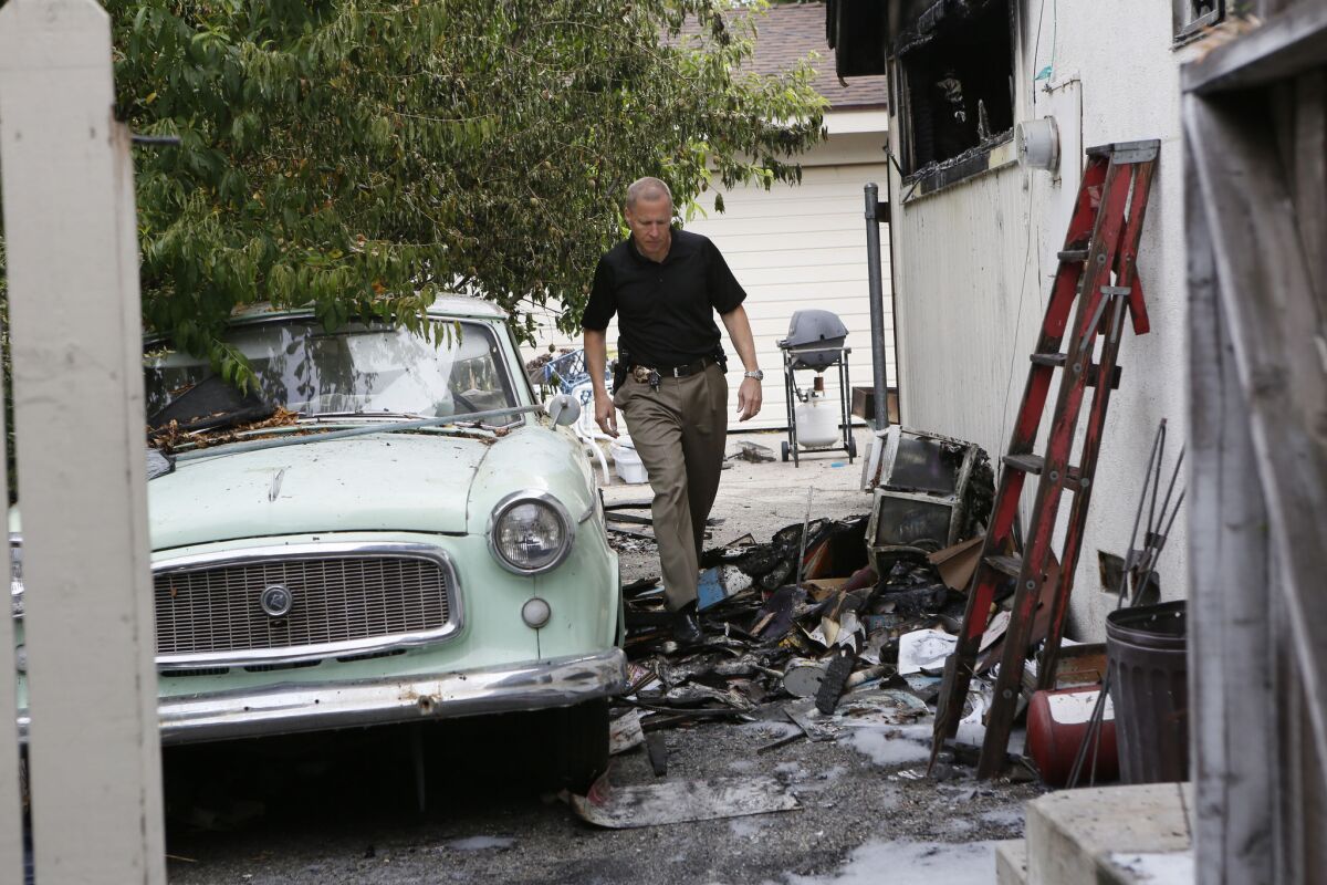 Glendora police Capt. Timothy Staab checks out the home in the 900 block of East Cypress Avenue, where a woman died and her husband was saved in a residential house fire.