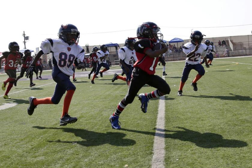 The youth football team Watts Bears (in white) pursue a member of the Southern California Falcons. Players are 7 to 9 years old.