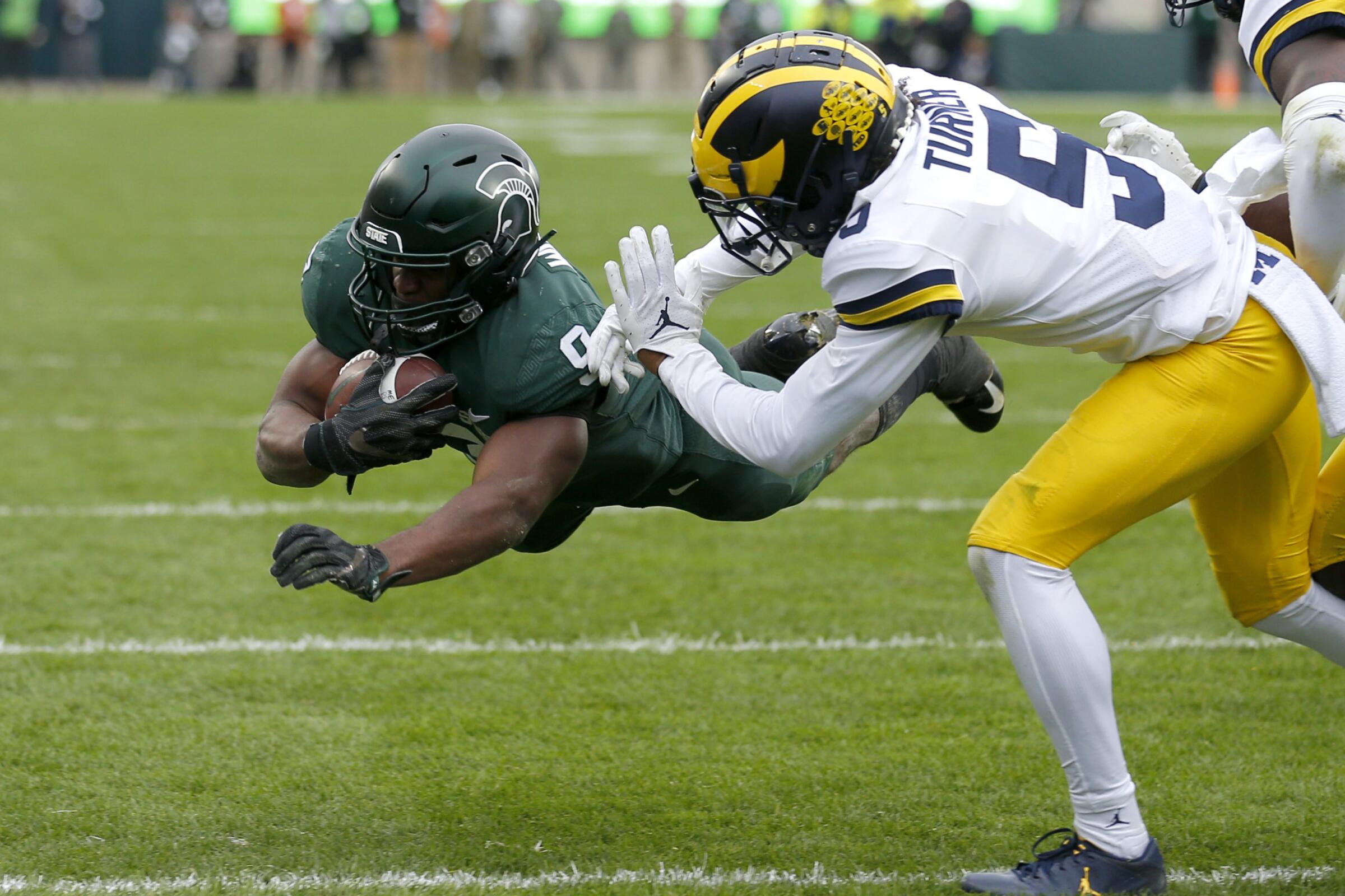 Michigan State running back Kenneth Walker dives over the goal line for a touchdown in front of Michigan's DJ Turner.