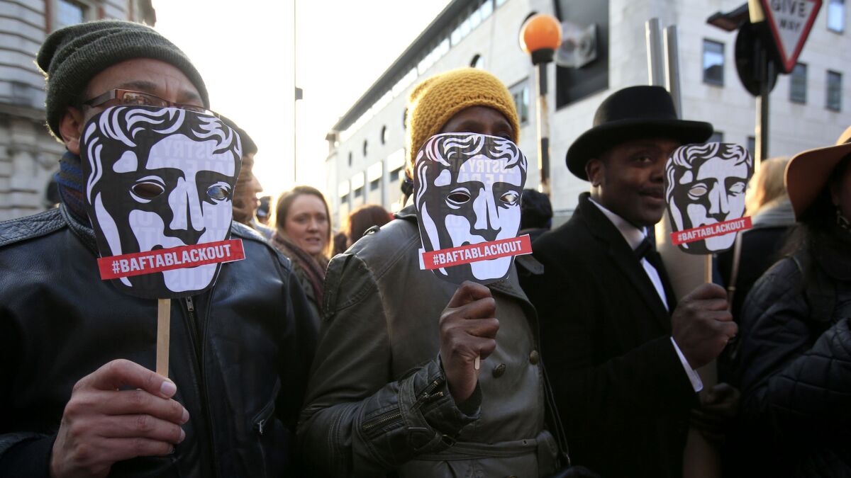 Protesters outside the site of the British Academy of Film and Television Arts awards show hold masks reading #BAFTABLACKOUT.