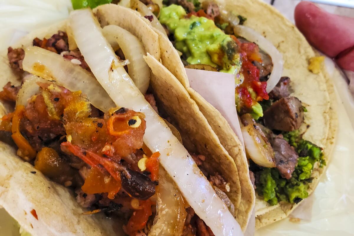 A close-up of two tacos topped with onions and guacamole.