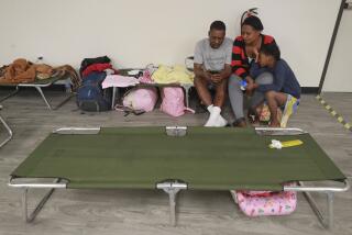 A family from Haiti sit on a cot at the newly relocated JFS Migrant Family Shelter on Friday, January 10, 2020 in San Diego, California.