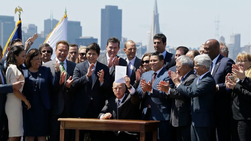 Gov. Jerry Brown holds up legislation extending California's cap-and-trade program during a signing ceremony July 25.