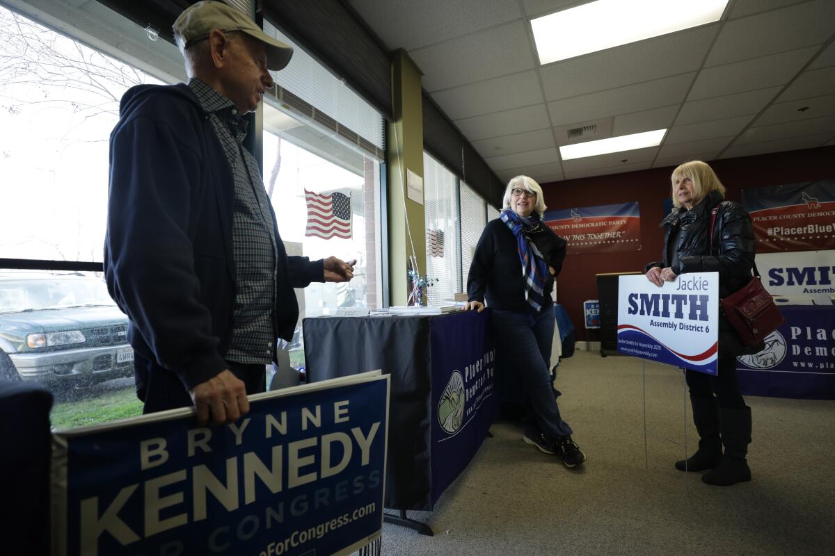 Rosemary Dukelow, center, speaks with Chuck and Audrey Ehrlich, who picked up lawn signs for Democratic candidates.