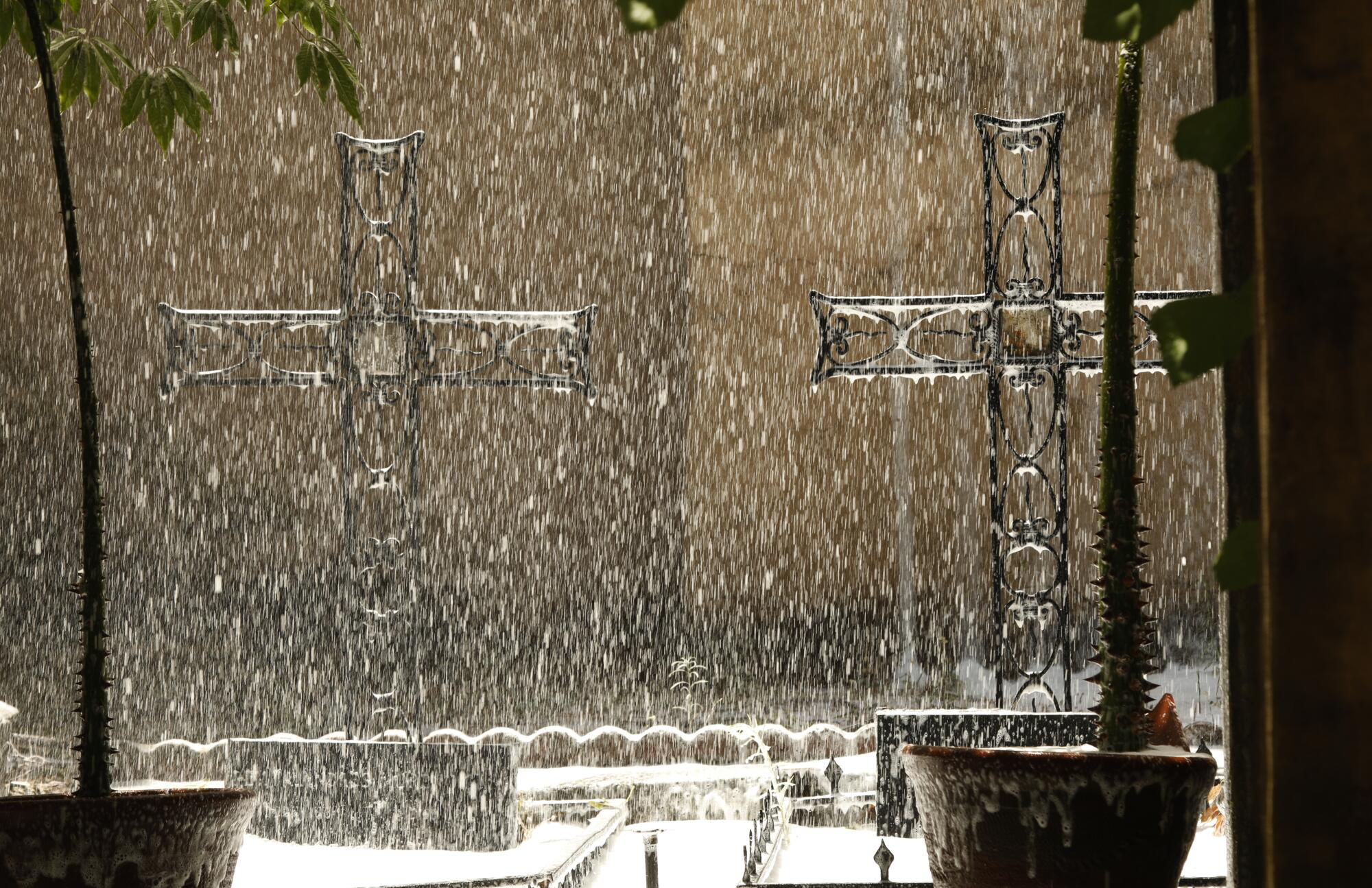 Foam that firefighters used to extinguish a massive fire falls on metal crucifixes on the grounds of the San Gabriel Mission