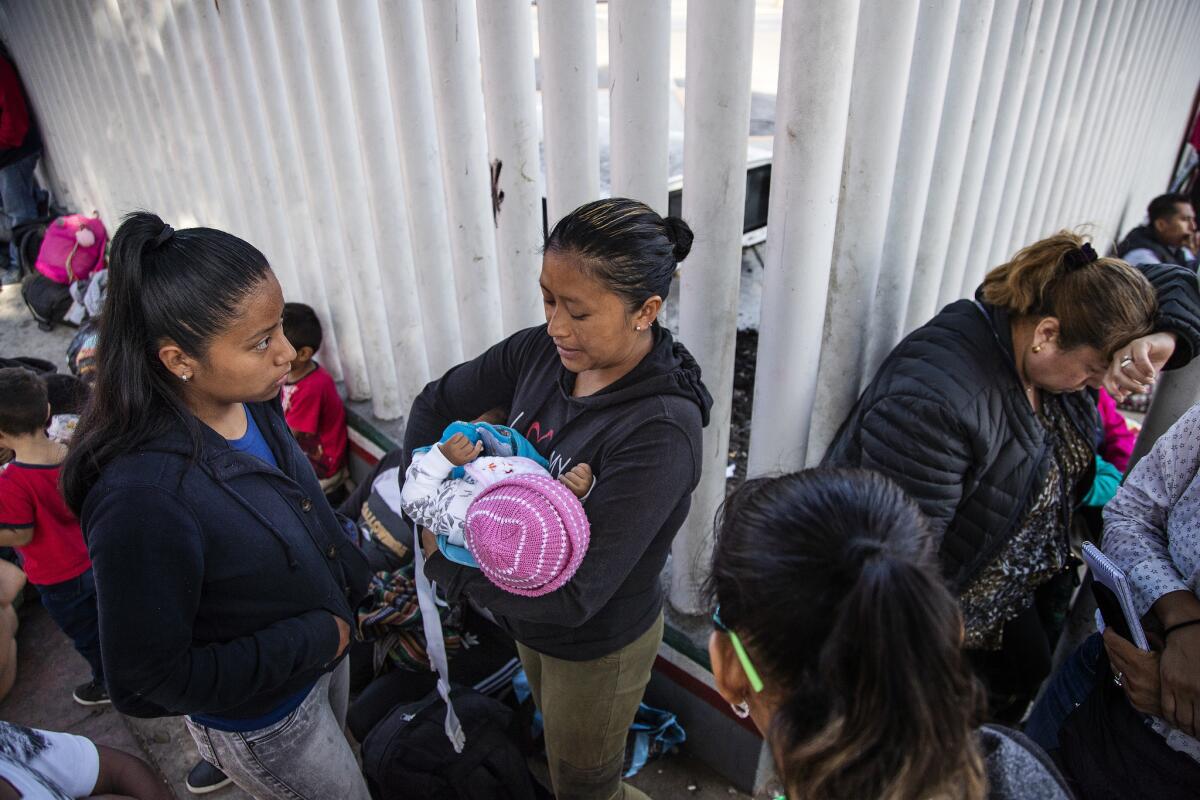 Dalila Pojoy holds 6-month-old Bernardethe while she and her other daughter Diana wait at the border. Pojoy says the brutality of her ex-boyfriend drove her to escape Mexico.