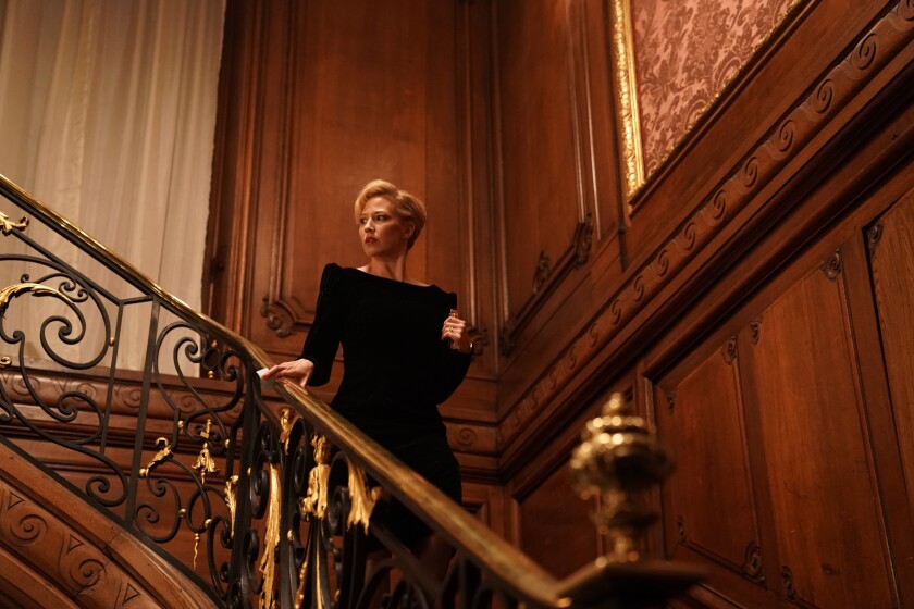 Carrie Coon stands on an elaborate staircase in "The Nest."