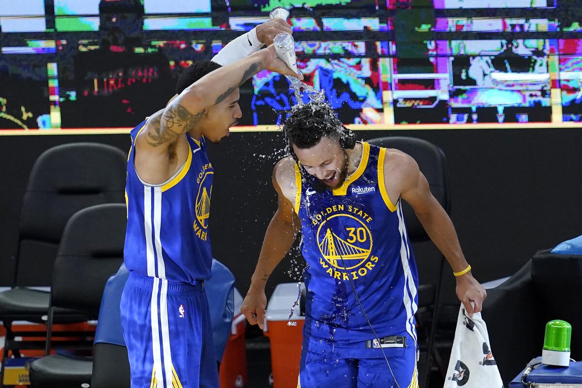 Golden State Warriors forward Juan Toscano-Anderson, left, pours water onto guard Stephen Curry (30) after the Warriors defeated the Denver Nuggets in an NBA basketball game in San Francisco, Monday, April 12, 2021. (AP Photo/Jeff Chiu)