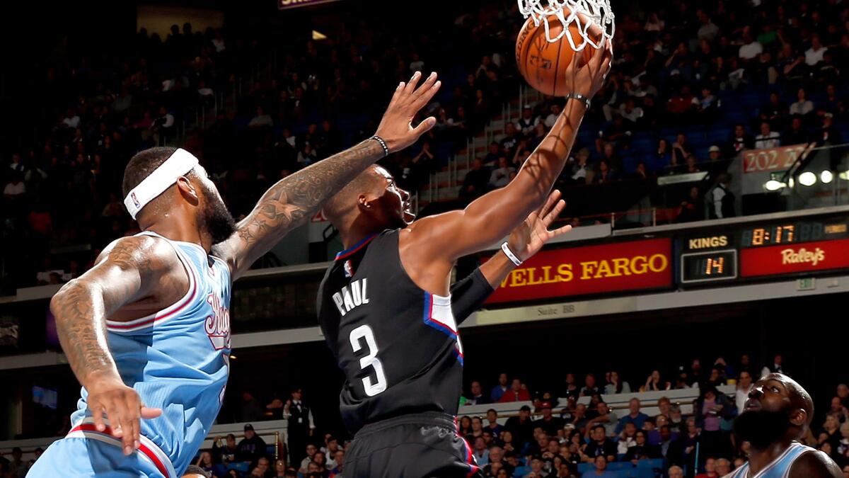 Clippers point guard Chris Paul gets past Kings center DeMarcus Cousins for a layup during the first half.