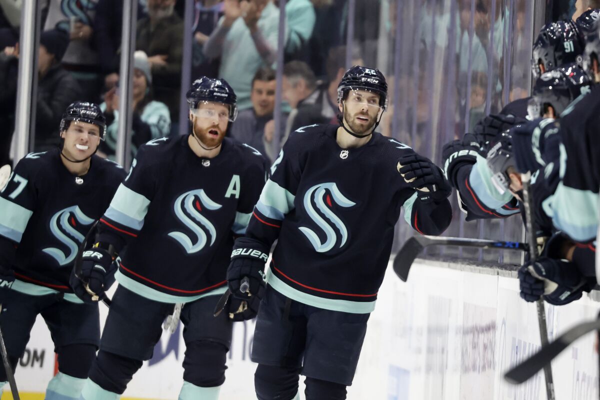 Seattle Kraken right wing Oliver Bjorkstrand (22) leads defenseman Adam Larsson (6) and center Yanni Gourde (37) after scoring against the Vancouver Canucks during the second period of an NHL hockey game Wednesday, Jan. 25, 2023, in Seattle. (AP Photo/John Froschauer)