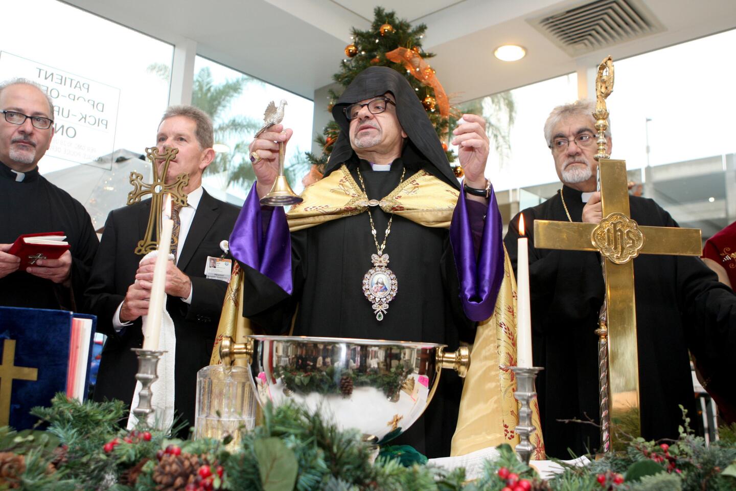 With Dignity Health Glendale Memorial Hospital and Health Center President Jack Ivie holding a cross, second from right, Western Prelacy of the Armenian Apostolic Church of America His Eminence Archbishop Moushegh Mardirossian blesses water, center, during the annual Armenian Christmas ceremony at the Glendale hospital on Thursday, Jan. 5, 2017.