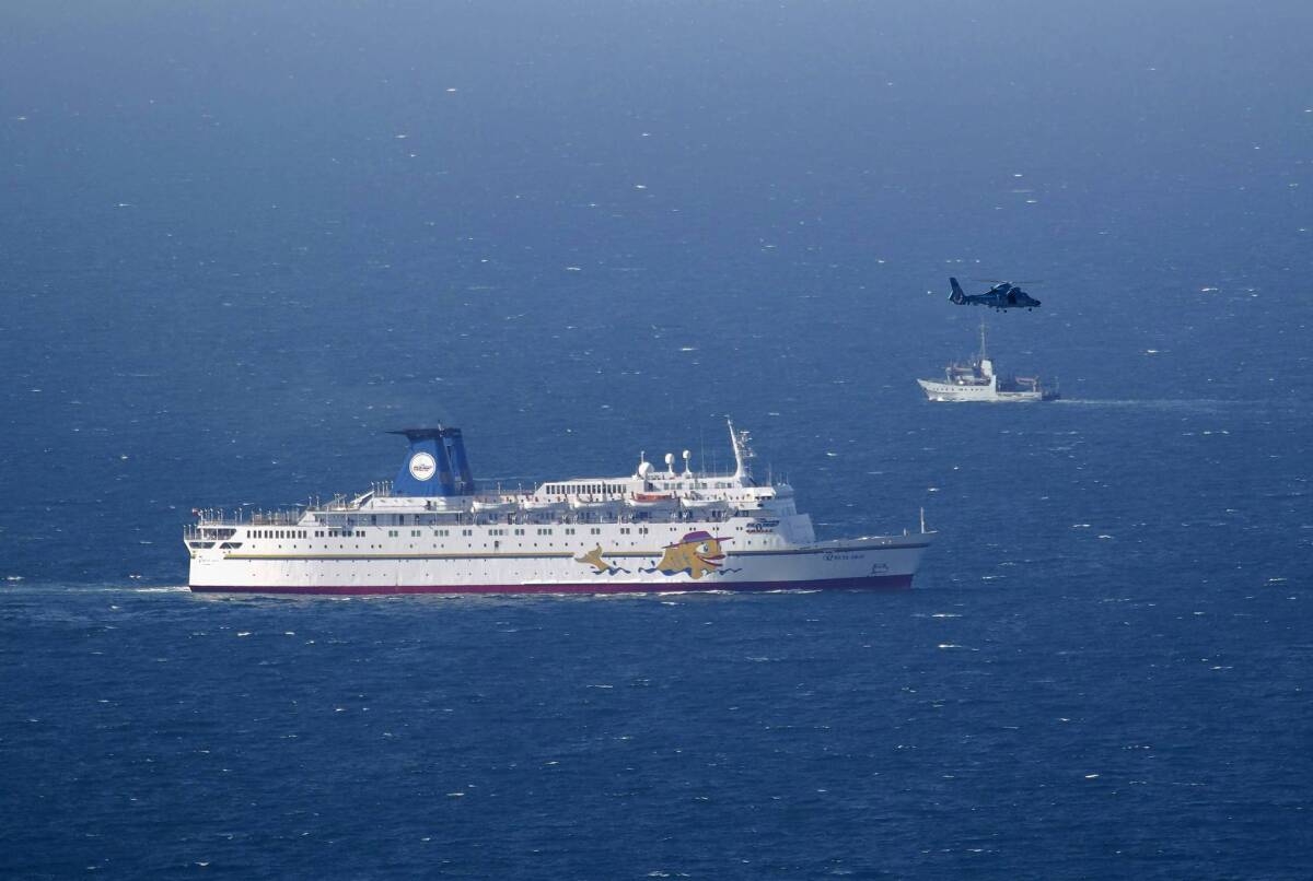 An Israeli military ship, background, and an air force helicopter operate next to a cruise ship off the coast of Haifa. The military said it shot down a drone five miles off the northern coast.