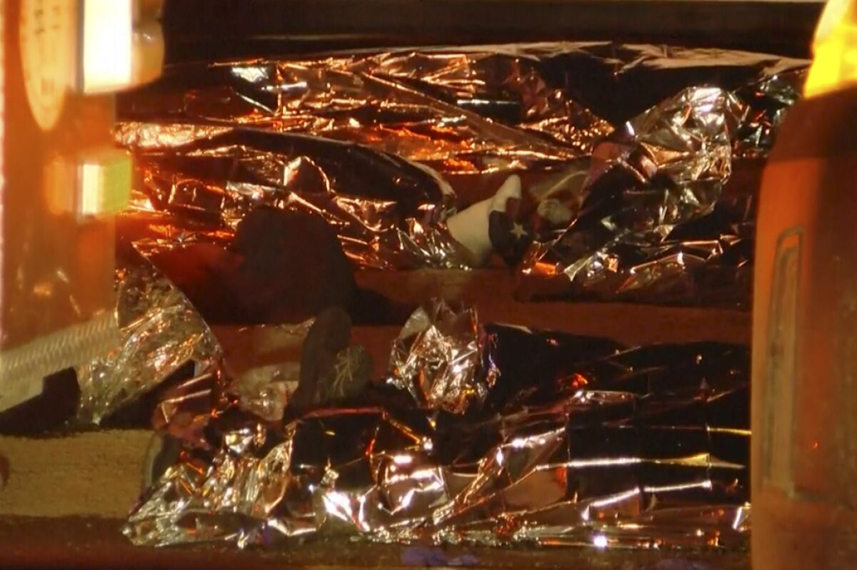 Esta imagen tomada de un video muestra cuerpos cubiertos por mantas de emergencia 