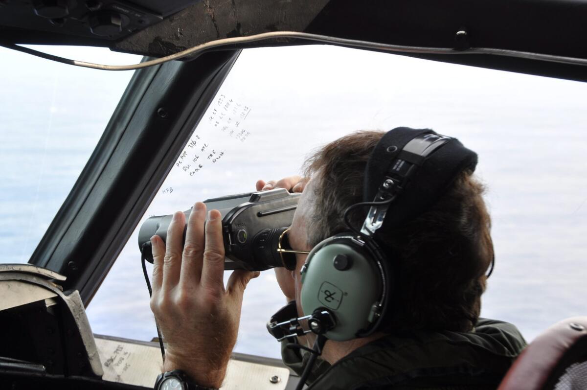 A Royal New Zealand Air Force P3 Orion Rescue Flight 795 crew member is seen during a search for debris from the missing Malaysia Airlines flight 370 northwest of Perth, Australia, over the Indian Ocean.