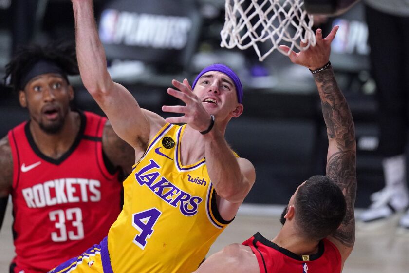 Los Angeles Lakers' Alex Caruso (4) goes up for a shot as Houston Rockets' Austin Rivers, right, defends.