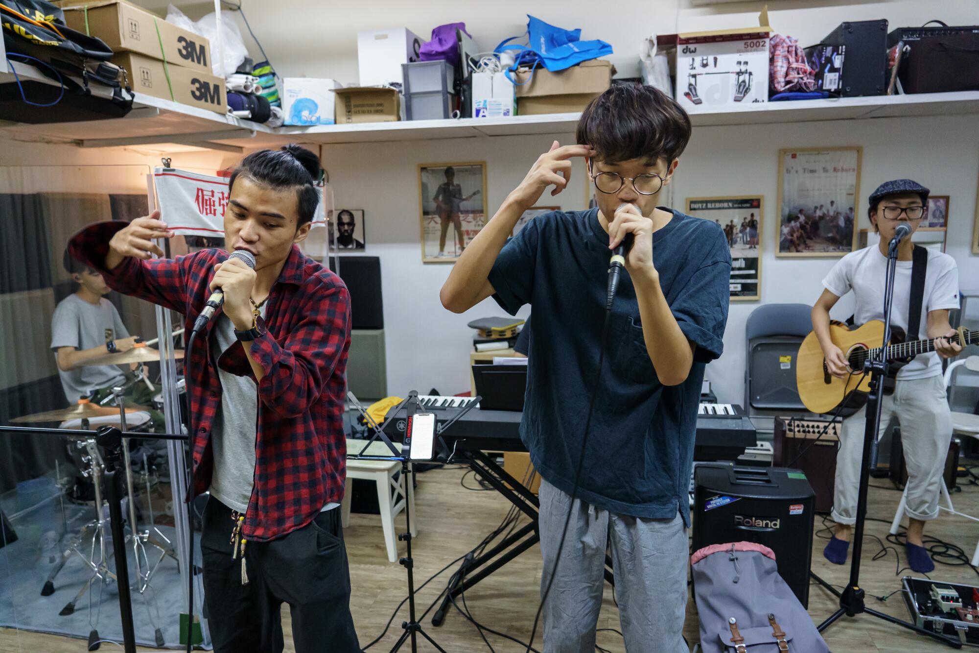 Jason Kwok, left, and Ben Chan mimic a gun to the head gesture, as they rehearse a song during band rehearsal in Hong Kong.