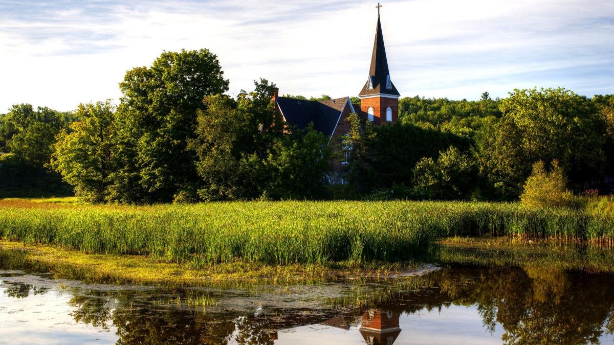 The United Church is reflected in a pond in Knowlton, Canada, a village in 蚕耻别产别肠’蝉 Eastern Townships that stands in as Three Pines in Louise Penny's books.