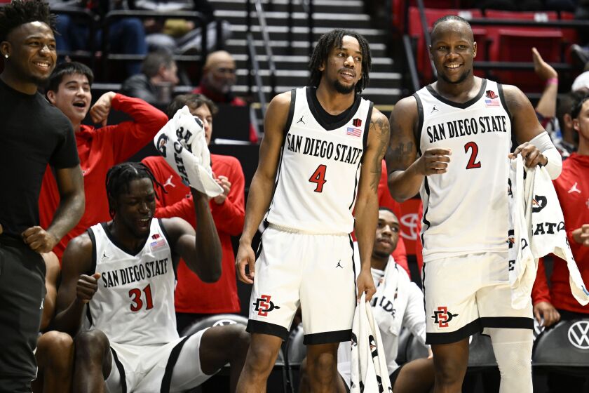 San Diego State forward Nathan Mensah (31), Jared Barnett (4) and Adam Seiko (2) watch from the bench area during the second half of the team's NCAA college basketball game against Occidental on Friday, Dec. 2, 2022, in San Diego. (AP Photo/Denis Poroy)
