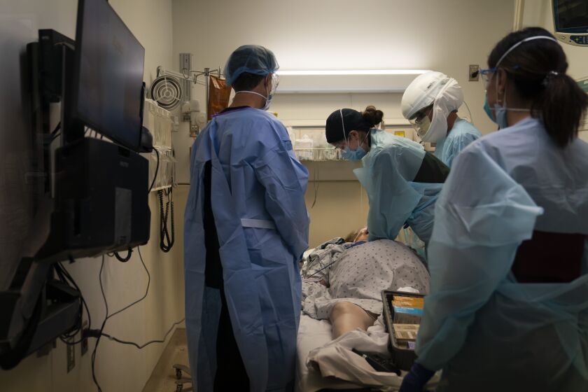 FILE - In this Nov. 19, 2020, file photo, EMT Giselle Dorgalli, third from right, performs chest compression on a patient who tested positive for coronavirus in the emergency room at Providence Holy Cross Medical Center in the Mission Hills section of Los Angeles. (AP Photo/Jae C. Hong, File)