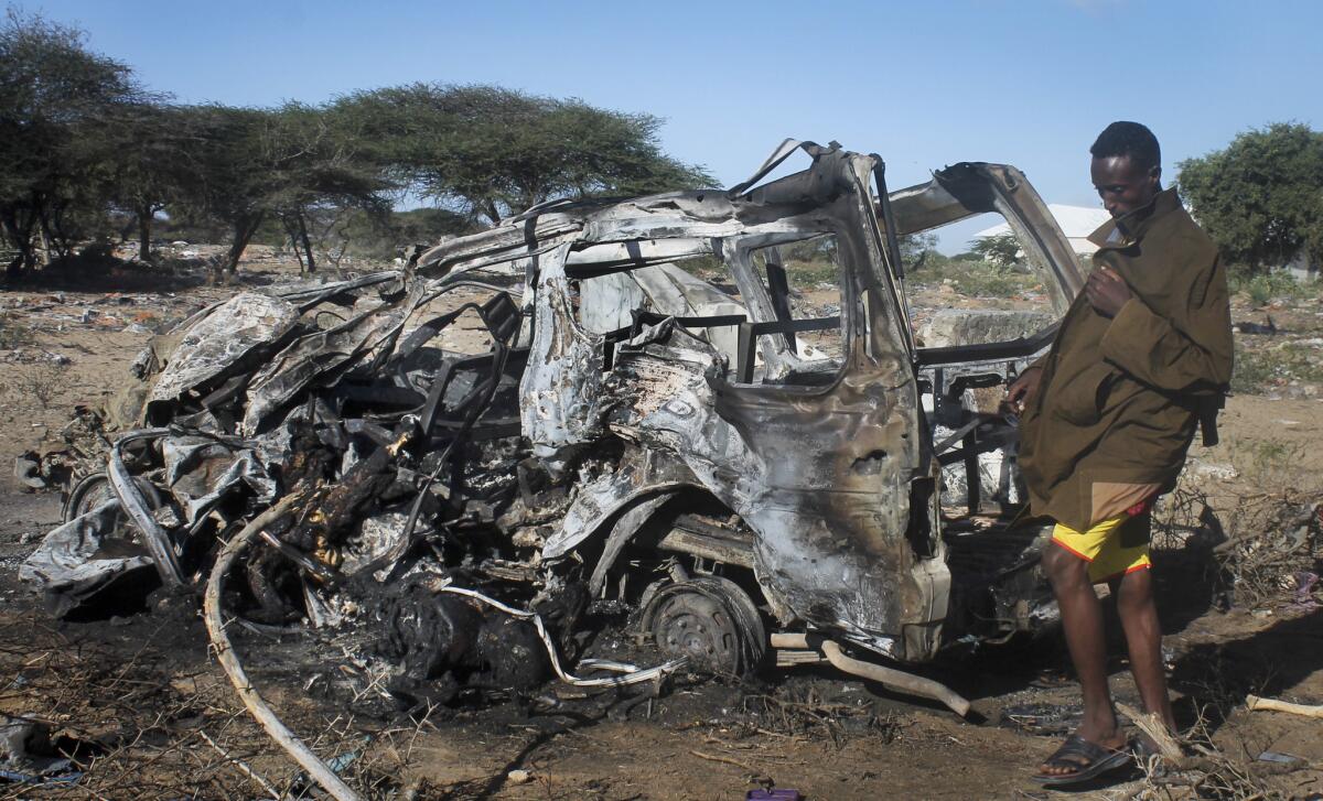 A Somali soldier stands near the wreckage of a civilian vehicle destroyed by a suicide car bomb attack south of Mogadishu, Somalia, Sept. 8.