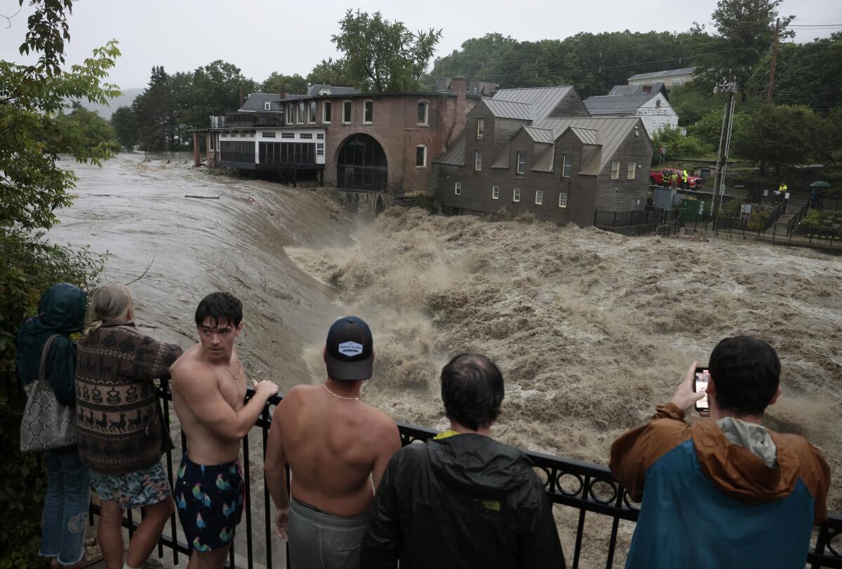 People watch the Ottauquechee River rise after extreme rainfall in Quechee, Vt., on July 10. 