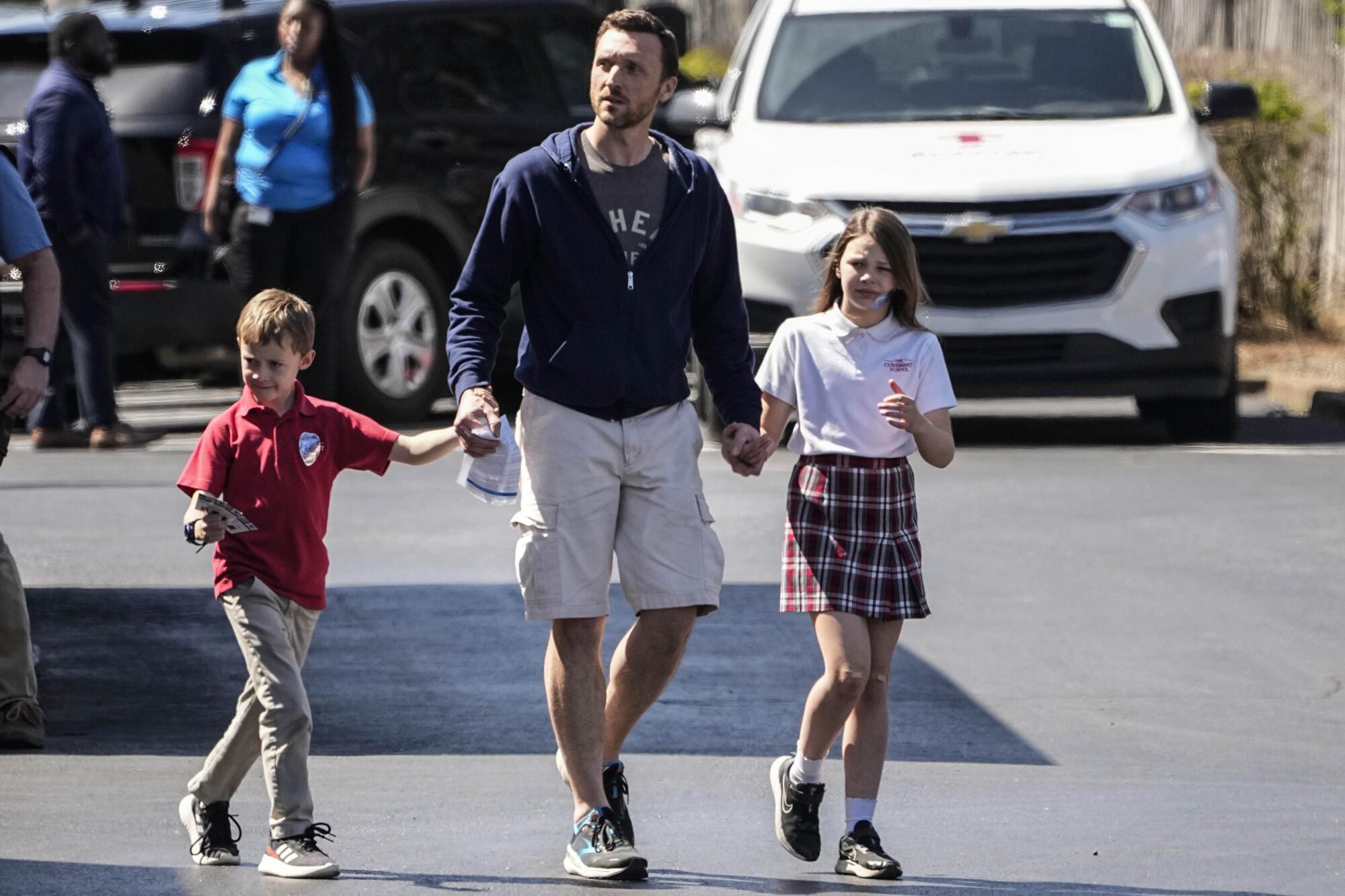 Two children walk holding hands with a man