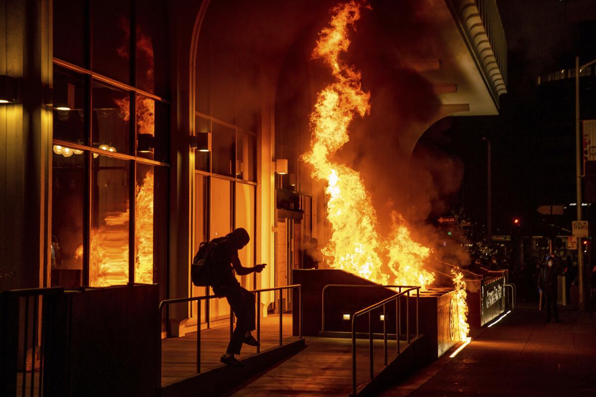 Demonstrators set fire to the front of the California Bank and Trust building during a protest against police brutality in Oakland, Calif., Friday, April 16, 2021. (AP Photo/Ethan Swope)