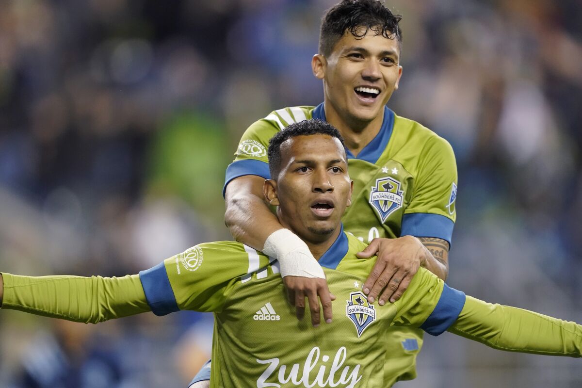 Seattle Sounders midfielder Leo Chu, bottom, celebrates with forward Fredy Montero after Chu scored a goal