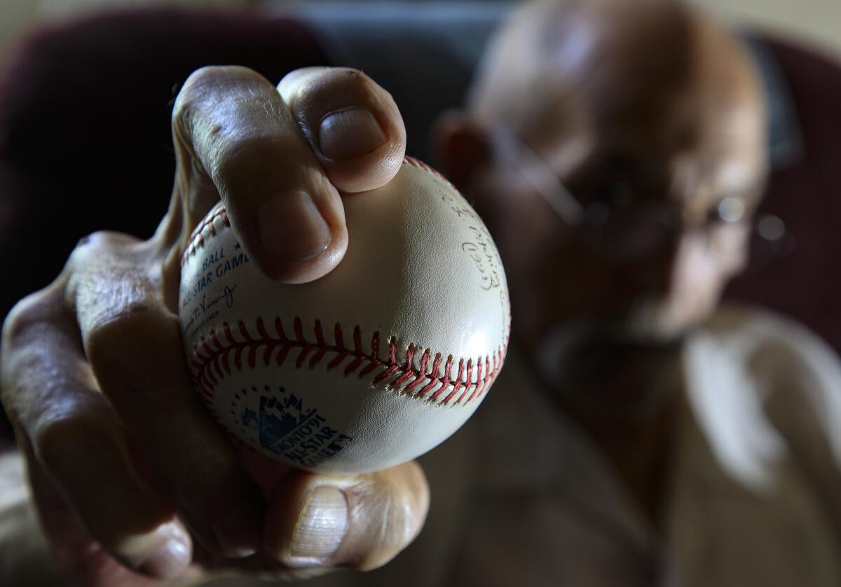 Stan Williams shows his fastball grip on a baseball from his collection in his Lakewood home. He pitched 14 seasons in the majors, primarily with the Dodgers and Yankees.